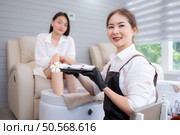 A moisturizing cream that a manicurist applies to massage a customer’s legs and feet in a foot spa. Стоковое фото, агентство Ingram Publishing / Фотобанк Лори