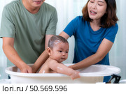 Parents bathe little child after ate meal. Стоковое фото, агентство Ingram Publishing / Фотобанк Лори