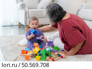 Grandmother and their little grandchild play happily in the living room of the house. Стоковое фото, агентство Ingram Publishing / Фотобанк Лори