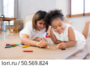 On a holiday, A woman and her little daughters sit on the floor and drawing together in the living room. Стоковое фото, агентство Ingram Publishing / Фотобанк Лори