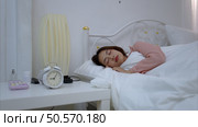Asian young woman on the bed in the bedroom trying to wake up and prepare for work. Стоковое фото, агентство Ingram Publishing / Фотобанк Лори