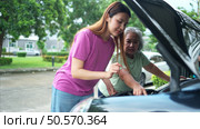 Grandmother and grandchild help each other execute a basic engine check on their parents’ automobile. Стоковое фото, агентство Ingram Publishing / Фотобанк Лори