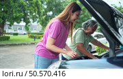 Grandmother and grandchild help each other execute a basic engine check on their parents’ automobile. Стоковое фото, агентство Ingram Publishing / Фотобанк Лори