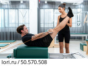 A young man and a young woman are doing pilates exercises on a pilates reformer. Стоковое фото, агентство Ingram Publishing / Фотобанк Лори