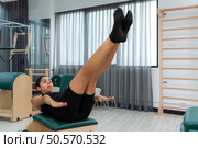 A young woman doing pilates exercises on a pilates reformer. Стоковое фото, агентство Ingram Publishing / Фотобанк Лори