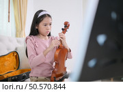 A girl violinist sets up and tunes a violin. Стоковое фото, агентство Ingram Publishing / Фотобанк Лори