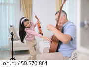 A girl violinist and her grandfather practice music together at home. Стоковое фото, агентство Ingram Publishing / Фотобанк Лори