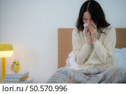 Asian woman feels unwell after waking up in the morning on a work day. Стоковое фото, агентство Ingram Publishing / Фотобанк Лори