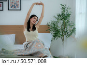 Asian woman feels well after waking up in the morning on a work day. Стоковое фото, агентство Ingram Publishing / Фотобанк Лори