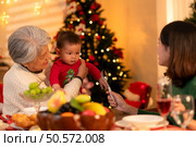 Grandmother, mother and little boy celebrate happily on Christmas night. Стоковое фото, агентство Ingram Publishing / Фотобанк Лори