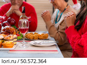 Grandfather leads a prayer and blessing before the family meal during the Christmas celebration at home. Стоковое фото, агентство Ingram Publishing / Фотобанк Лори