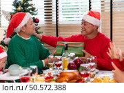 Family members are exchanging gifts with each other in the dinner time during the Christmas holiday at home. Стоковое фото, агентство Ingram Publishing / Фотобанк Лори