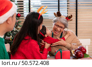 A little granddaughter lovingly hugs her grandmother, while they eating a meal together during the Christmas celebration at home. Стоковое фото, агентство Ingram Publishing / Фотобанк Лори