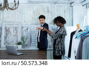 In a modern clothes fashion room, a clothing designer or tailor allows buyers to try on molded outfits before sewing them. Стоковое фото, агентство Ingram Publishing / Фотобанк Лори