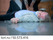 An elderly businessman suffered a sudden heart failure at work, A coworker was administering CPR to offer basic life support. Стоковое фото, агентство Ingram Publishing / Фотобанк Лори