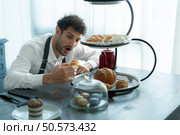 A young man puts on an apron to make dessert to eat with his wife. Checking the completeness of the finished dessert. Стоковое фото, агентство Ingram Publishing / Фотобанк Лори