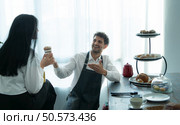 A husband wears an apron while cooking dinner with his wife. The duo took a break to sip coffee and sample the completed bread. Стоковое фото, агентство Ingram Publishing / Фотобанк Лори