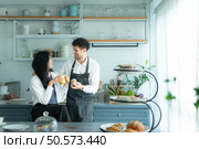 A husband wears an apron while cooking dinner with his wife. The duo took a break to sip coffee and sample the completed bread. Стоковое фото, агентство Ingram Publishing / Фотобанк Лори