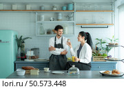 A husband wears an apron while cooking dinner with his wife. The duo took a break to sip coffee and sample the completed bread. Стоковое фото, агентство Ingram Publishing / Фотобанк Лори
