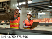 Male and female engineers work together in an electric repair station. Inspecting the undercarriage of electric train that are being repaired at the garage. Стоковое фото, агентство Ingram Publishing / Фотобанк Лори