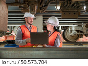 Male and female engineers work together in an electric repair station. Inspecting the undercarriage of electric train that are being repaired at the garage. Стоковое фото, агентство Ingram Publishing / Фотобанк Лори