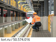 Portrait of a young male technician using a blueprint working and standing in a skytrain repair station. Стоковое фото, агентство Ingram Publishing / Фотобанк Лори