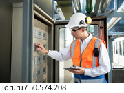 Before proceeding with the testing, Electrical engineer inspects the installed control panel. Стоковое фото, агентство Ingram Publishing / Фотобанк Лори