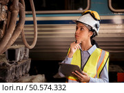 Portrait of railway technician worker in safety vest and helmet working with blueprint at train repair station. Стоковое фото, агентство Ingram Publishing / Фотобанк Лори