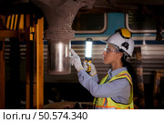 Portrait of railway technician worker in safety vest and helmet working with blueprint at train repair station. Стоковое фото, агентство Ingram Publishing / Фотобанк Лори