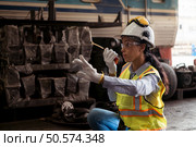 Portrait of railway technician worker in safety vest and helmet working with blueprint at train repair station. Стоковое фото, агентство Ingram Publishing / Фотобанк Лори