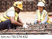 Railway technicians worker in safety vest and helmet inspect the battery in the train workshop. Стоковое фото, агентство Ingram Publishing / Фотобанк Лори