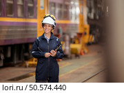 Portrait of railway technician worker in safety vest and helmet working and using a walkie talkie at train repair station. Стоковое фото, агентство Ingram Publishing / Фотобанк Лори