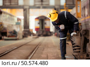 Railway technician in uniform and helmet inspect the train wheels removed from the locomotives in the train workshop. Стоковое фото, агентство Ingram Publishing / Фотобанк Лори