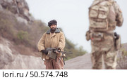 A Taliban soldier stands with a machine gun, Surrender to the allied soldiers, In the desert mountain terrain battlefield. Стоковое фото, агентство Ingram Publishing / Фотобанк Лори