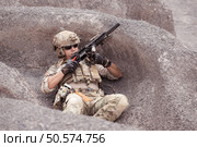 A Taliban soldier stands with a machine gun, Surrender to the allied soldiers, In the desert mountain terrain battlefield. Стоковое фото, агентство Ingram Publishing / Фотобанк Лори