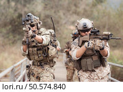 Soldiers in camouflage military uniforms carrying weapons, Reconnaissance missions in the tropical forest area, Assault infantry battle training. Стоковое фото, агентство Ingram Publishing / Фотобанк Лори