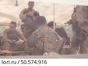 Group of soldiers in camouflage uniforms hold weapons in a field tent, Plan and prepare for combat training. Стоковое фото, агентство Ingram Publishing / Фотобанк Лори