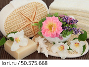 Spa arrangement of herb and flower leaf sprigs, cream towels, exfloiating scrub, coral and  natural soap over bamboo. Стоковое фото, агентство Ingram Publishing / Фотобанк Лори