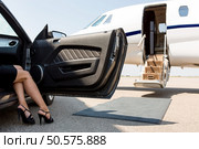 Low section of wealthy woman stepping out of car parked in front of private plane. Стоковое фото, агентство Ingram Publishing / Фотобанк Лори