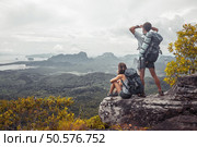 Couple of tourist with backpacks relaxing on top of a mountain and enjoying the view of valley. Hikers on the mountain. Стоковое фото, агентство Ingram Publishing / Фотобанк Лори