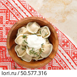dumplings with dill and sour cream in wooden plate on rustic towel with red pattern. top view. Стоковое фото, агентство Ingram Publishing / Фотобанк Лори