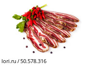 Slices of spicy smoked bacon decorated with chili peppers, on white background.. Spicy Smoked Bacon Sliced. Стоковое фото, агентство Ingram Publishing / Фотобанк Лори