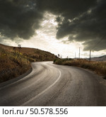 a winding road in countryside with gloomy cloudscape at the sunset . Стоковое фото, агентство Ingram Publishing / Фотобанк Лори