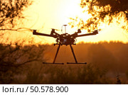 Drone on a background of a beautiful sunset. UAV in flight. Quadrocopters on radio.. Oktokopter, copter, drone. Стоковое фото, агентство Ingram Publishing / Фотобанк Лори