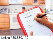 Closeup of a contractors clipboard as he writes up an estimate for a kitchen remodel. Shallow depth of field with focus on clipboard. Стоковое фото, агентство Ingram Publishing / Фотобанк Лори