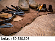 Set of leather craft tools on wooden background. Workplace for shoemaker. Piece of hide and working handmade tools on a work table.. Set of leather craft tools on wooden background. Workplace for shoemaker. Стоковое фото, агентство Ingram Publishing / Фотобанк Лори