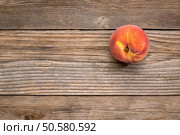 single fresh peach fruit on weathered grained wood with a copy space. Стоковое фото, агентство Ingram Publishing / Фотобанк Лори