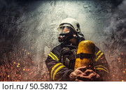 Firefighter in oxygen mask holds yellow oxygen tank. Стоковое фото, агентство Ingram Publishing / Фотобанк Лори