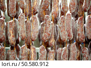 Close up of many freshly packed sausages left hanging to be cured in meat processing plant. Freshly packed sausages curing in factory. Стоковое фото, агентство Ingram Publishing / Фотобанк Лори