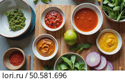 A food stylist's workspace with bowls of vibrant sauces. bright green herb pesto, deep red harissa, golden turmeric aioli arranged on beautiful modern kitchen. Стоковое AI-видео, аниматор Sergey Grishin / Фотобанк Лори